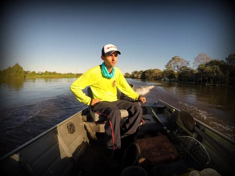 Pescador no barco pelo Rio Miranda